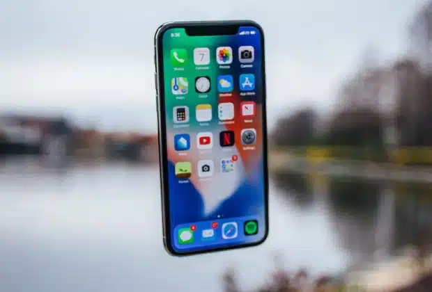 silver iPhone X floating over open palm